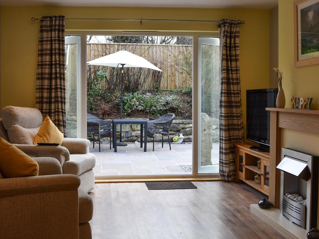 a living room with a sliding glass door leading to a patio at Old Orchard Cottage Near Eden in Luxulyan