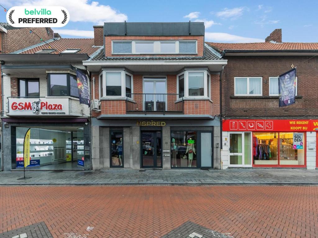 a building on a brick street with stores at Maasmechelen Duplex Retreat in Maasmechelen
