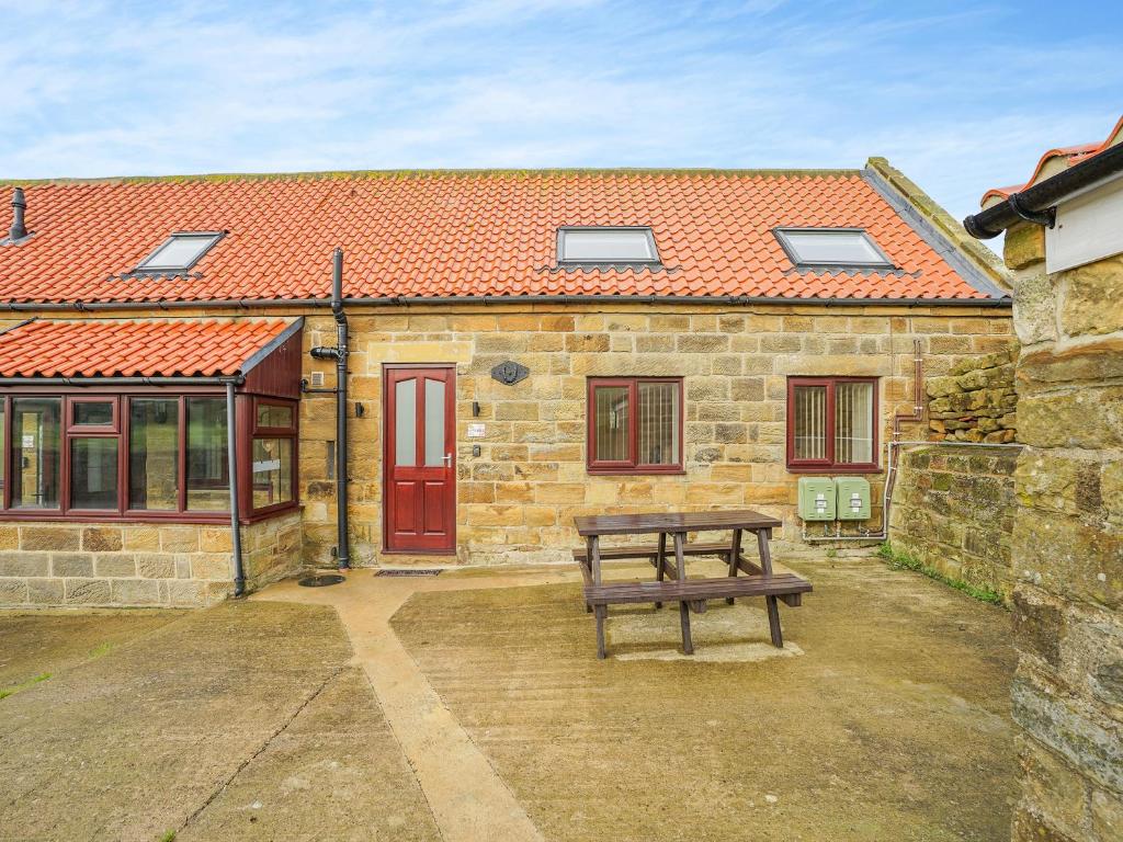 a bench in front of a stone building with a red door at Harebell- Uk45262 in Whitby