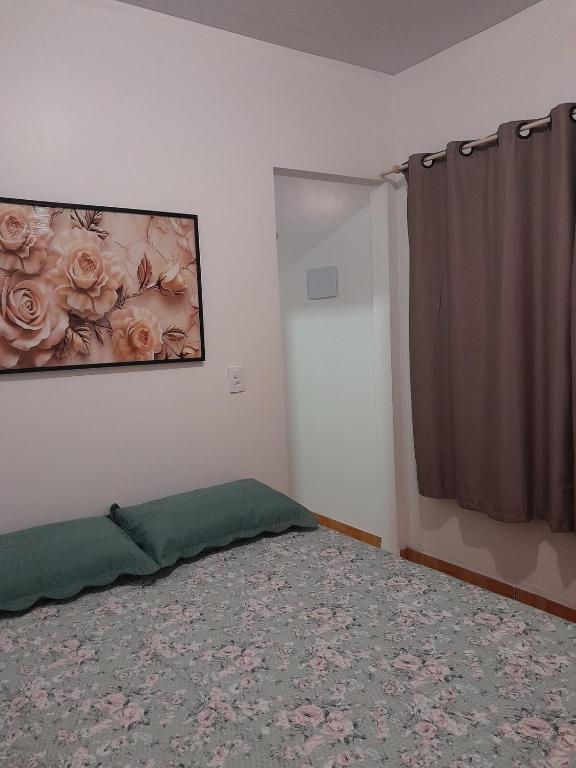 a bedroom with a bed and a painting of roses at Pousada Baden Baden in Blumenau