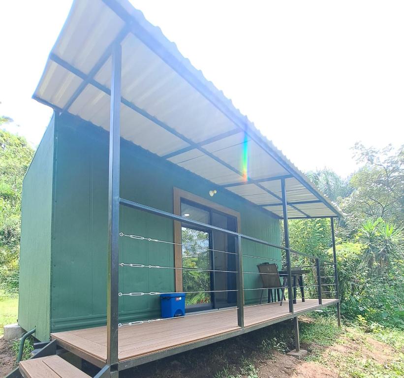 a green house with a porch and a table at Contenedor el Colibrí in Naranjo