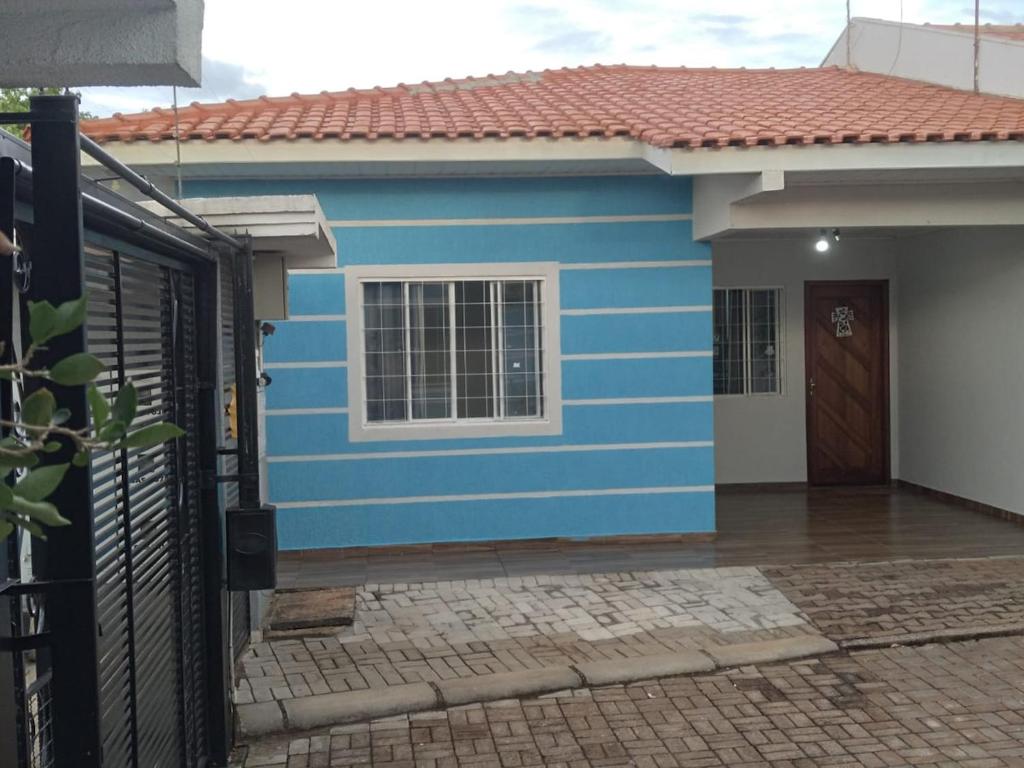 une maison bleue avec une fenêtre blanche et une porte dans l'établissement Casa em condomío, bem localizada, à Cascavel