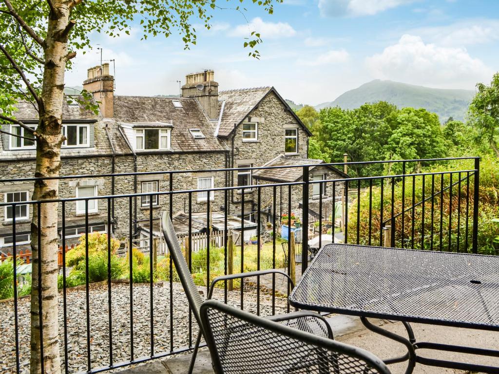 einen Tisch und Stühle auf einem Balkon mit einem Haus in der Unterkunft Fairfield Cottage in Ambleside