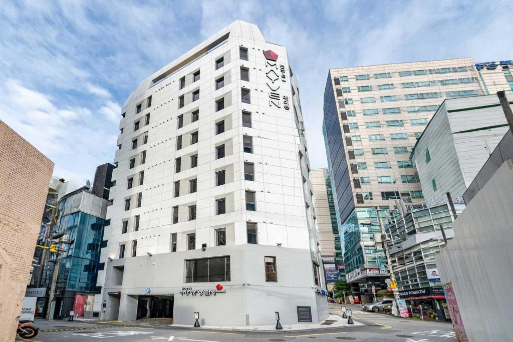 a tall white building in the middle of a city at Shinchon Mayven Hotel - Foreign Tourist Tax Return Hotel in Seoul