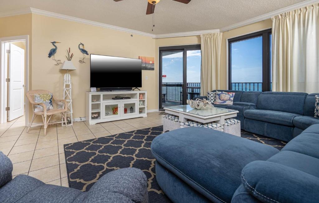 a living room with blue couches and a flat screen tv at Phoenix VI 61408 in Orange Beach