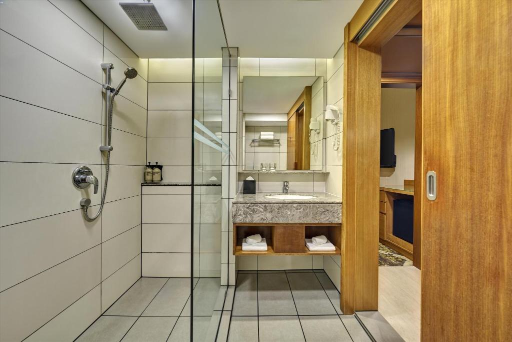 A tiled bathroom showing a walk-in shower, vanity and adjoining wardrobe doorway.