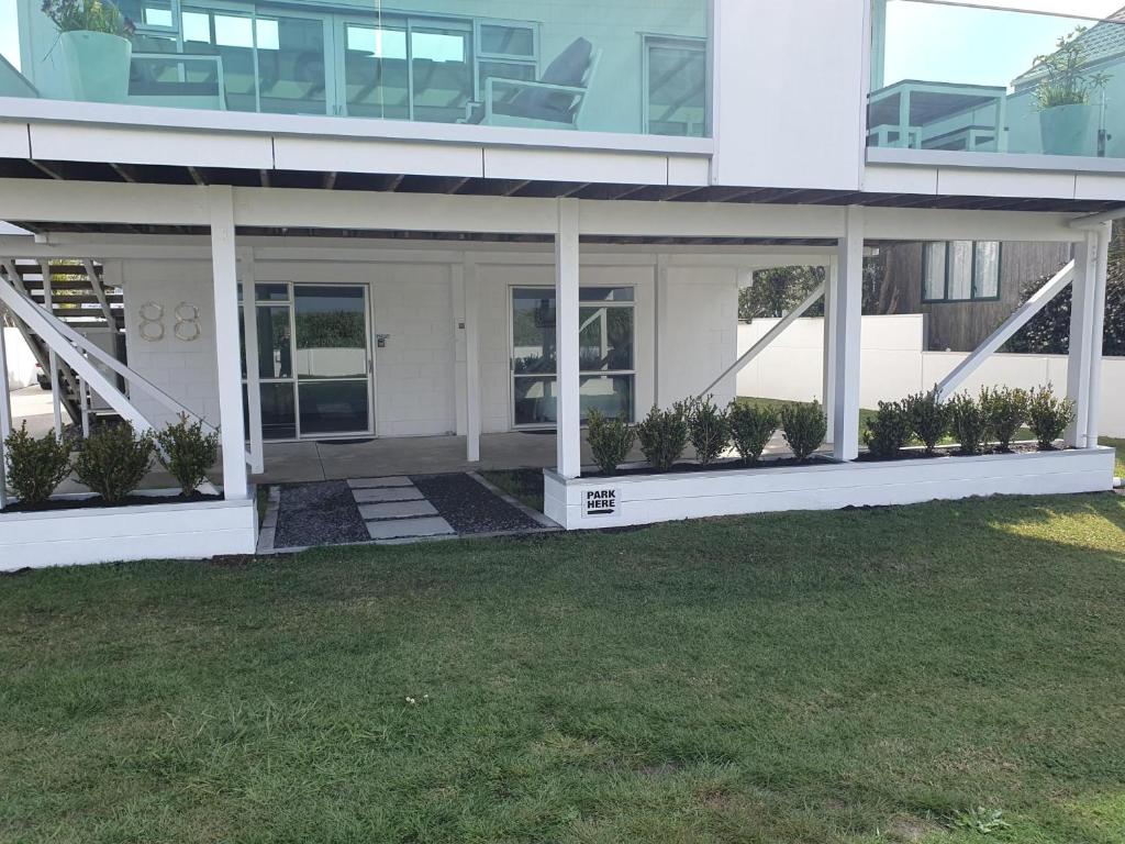 a large white building with plants in front of it at Bronny's Beachfront BnB in Whitianga