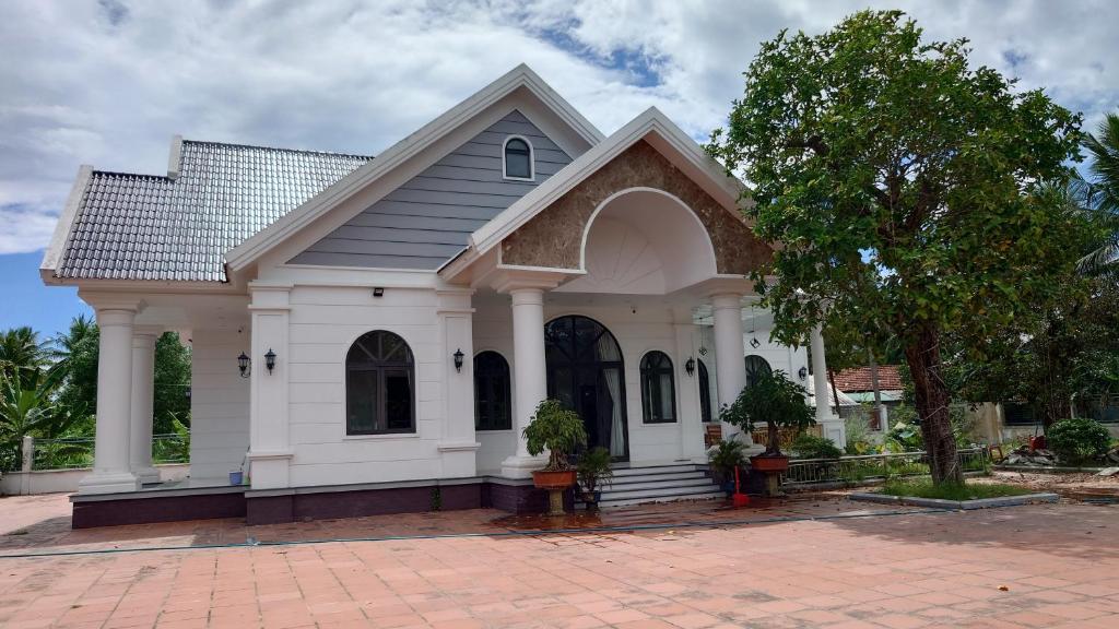 une petite maison blanche avec un arbre en face dans l'établissement Khách sạn Lavender Hoa châu resort, 