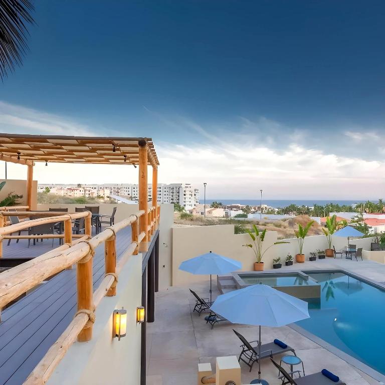 a balcony with a pool and patio furniture and umbrellas at Spacious Pool Side Condo - SJD in San José del Cabo