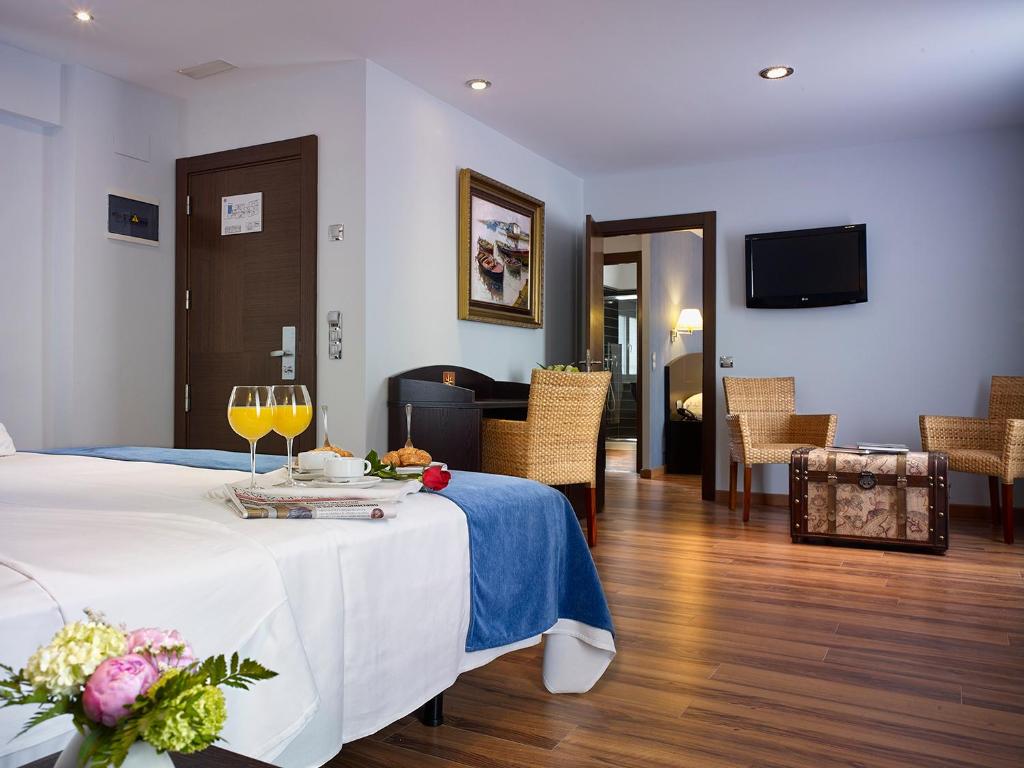 una habitación de hotel con una mesa con copas de vino. en Hotel La Serrana, antiguo 40 Nudos, en Avilés