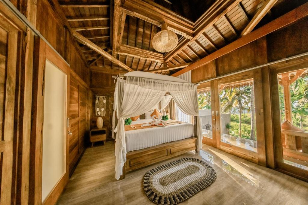 a bedroom with a bed in a room with wooden walls at Sunsura Villas in Nusa Penida