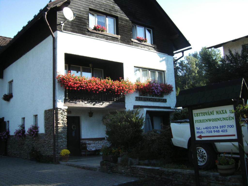 uma casa branca com caixas de flores nas janelas em Ubytování Maxa em Špičák