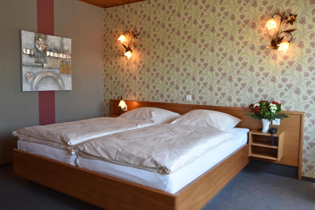 a bedroom with a large bed with white sheets at Hotel Haus Tiefenbach in Bullange