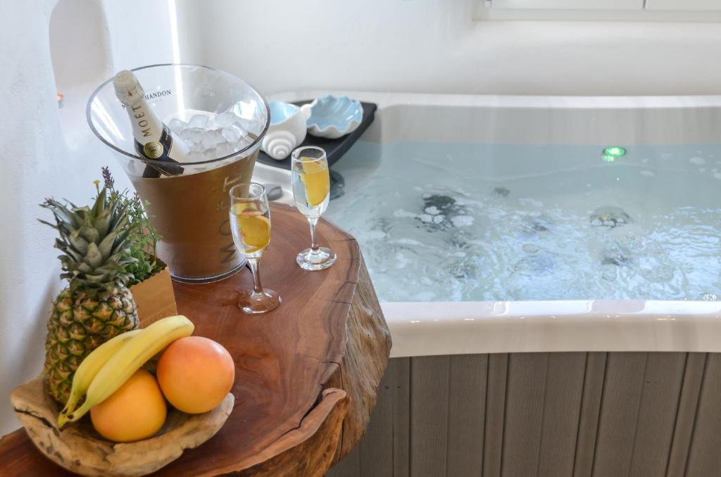 a tray of fruit and glasses of champagne in a bath tub at Naxos Island Escape Suites in Plaka