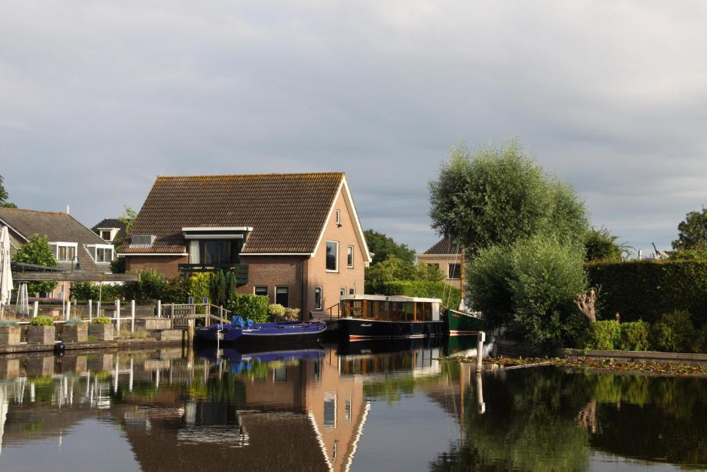 una casa y un barco en un río con casas en Gastenverblijf De Kapitein, en Nieuwkoop