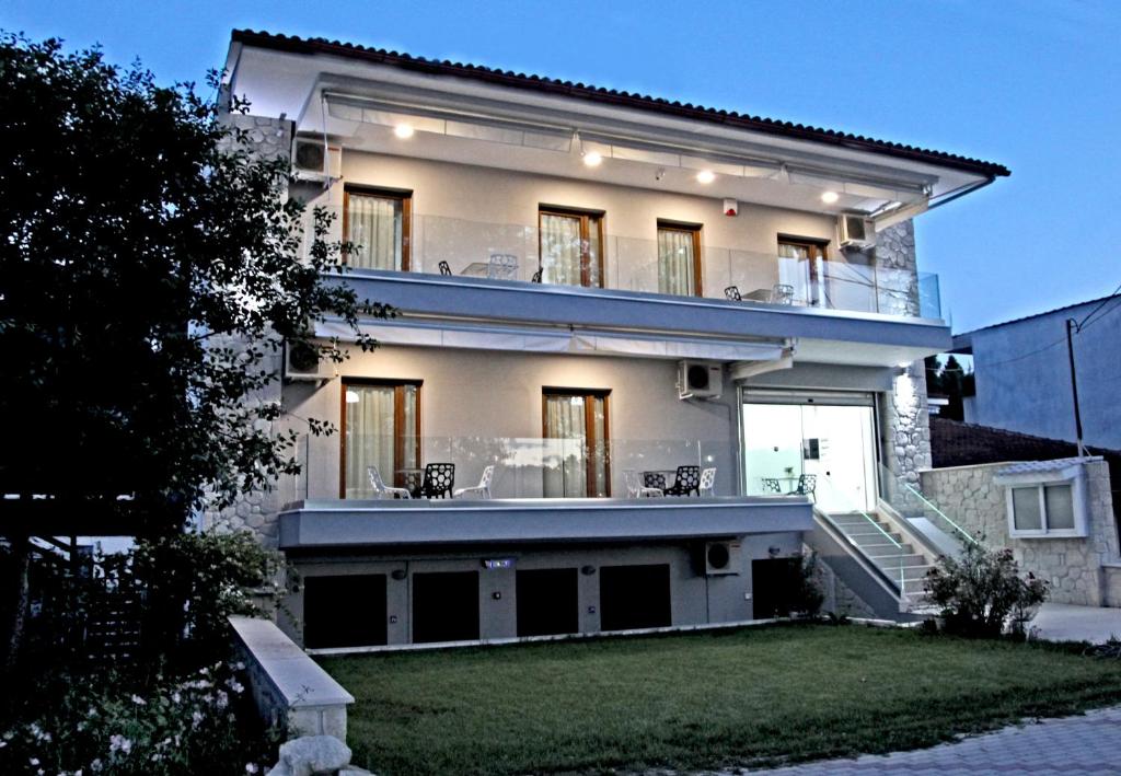 uma grande casa branca com uma varanda e um quintal em Kochili Seashell Apartments em Siviri