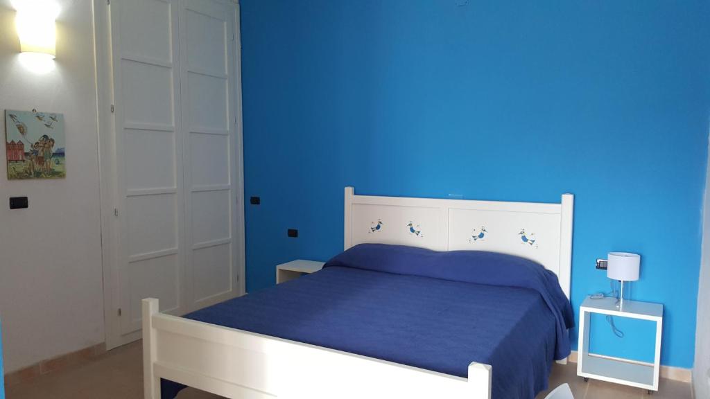een blauwe slaapkamer met een bed met een blauwe muur bij Casa con ampio giardino Sulcis in Giba
