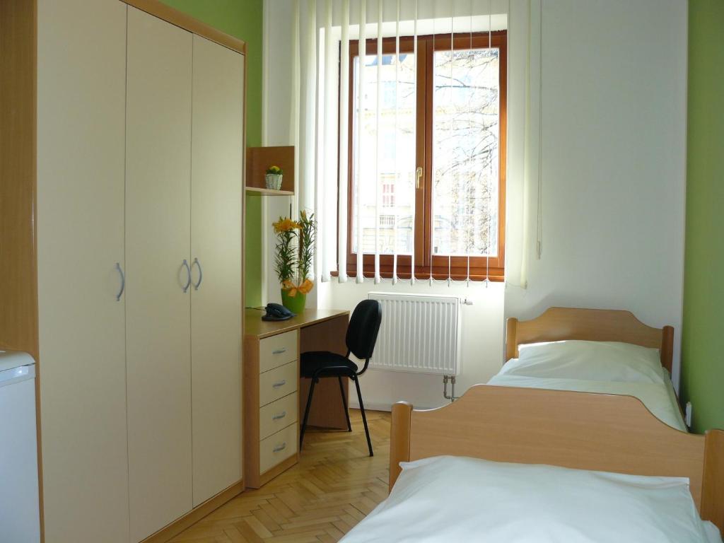 a bedroom with two beds and a desk and a window at Ubytovna Marie in Olomouc