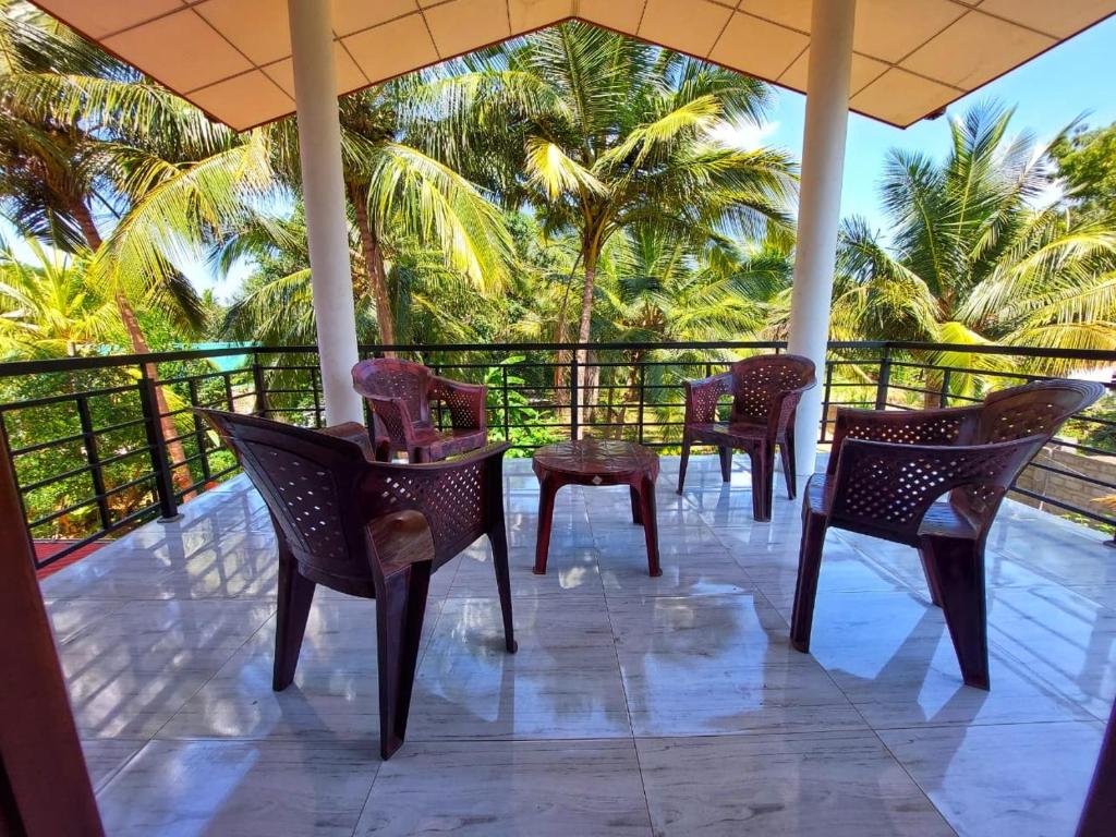 a row of chairs on a porch with palm trees at Wijaya Home Stay in Anuradhapura
