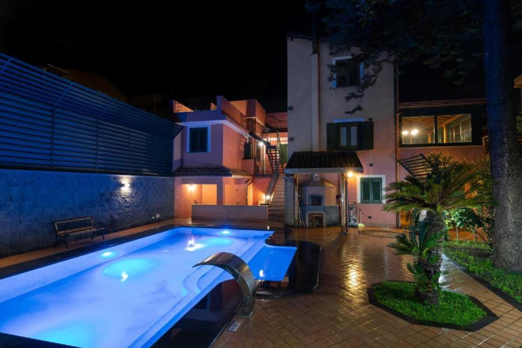 a large swimming pool in a yard at night at Alhambra "Etna Charme" - Guest House in Giarre
