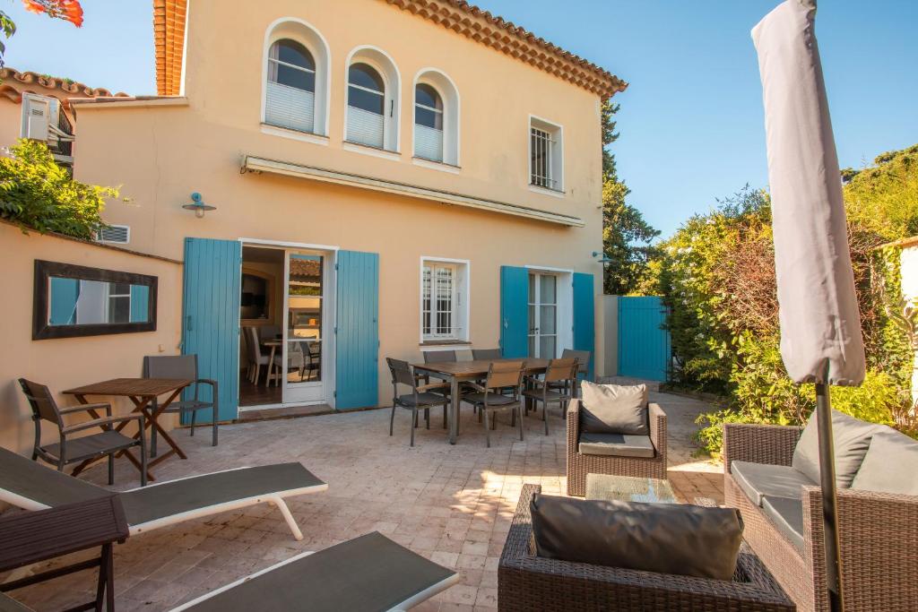 un patio con mesas y sillas frente a una casa en Maison Ferienhaus Grillons, en Saint-Tropez