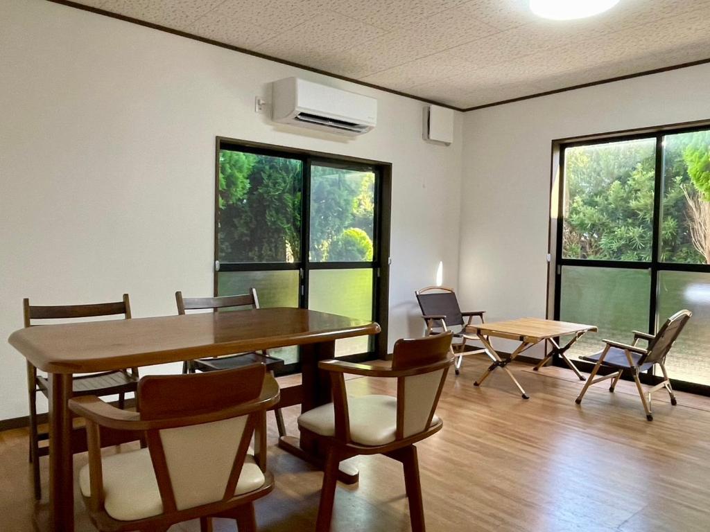 a dining room with a table and chairs and windows at いちほの宿 友秀 in Makinohara