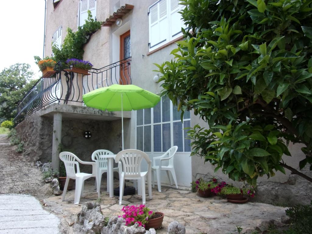 eine Terrasse mit einem Tisch, Stühlen und einem Sonnenschirm in der Unterkunft Appartement L'oranger in Pégomas