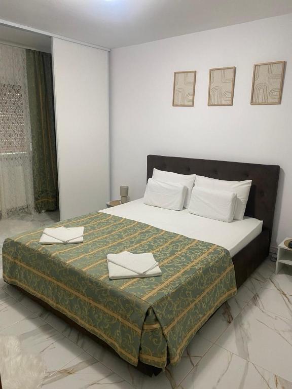 een slaapkamer met een groot bed met twee servetten erop bij Lemora Apartments in Focşani