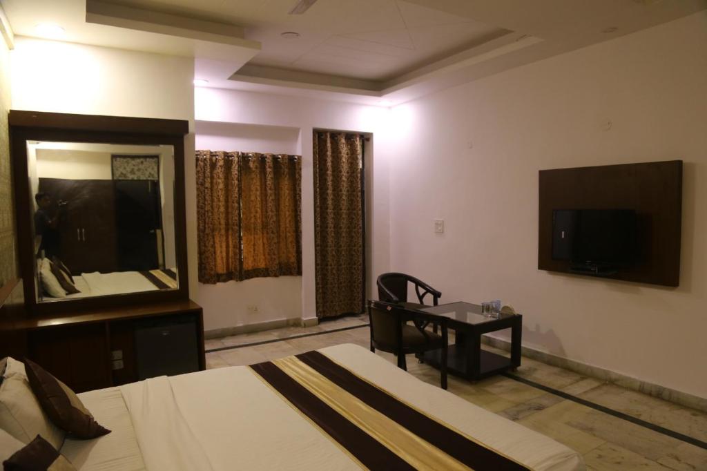 a bedroom with a bed and a desk and a television at Rockwood Inn in Faridabad