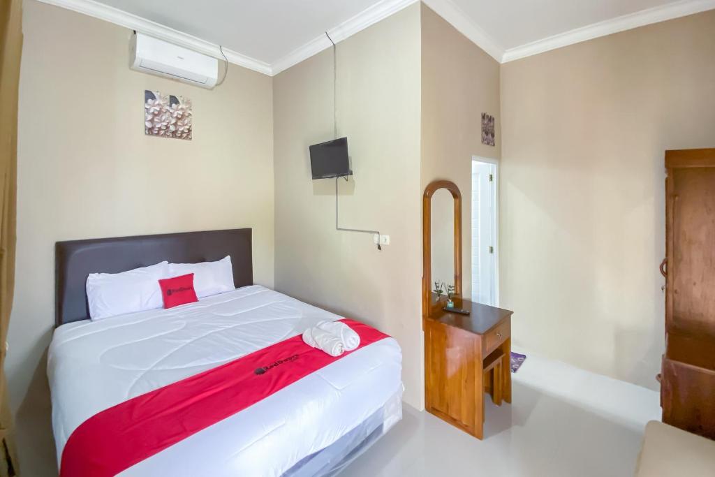 a bedroom with a large bed and a bath tub at RedDoorz at Kamulyan Guest House Borobudur in Sekatonan