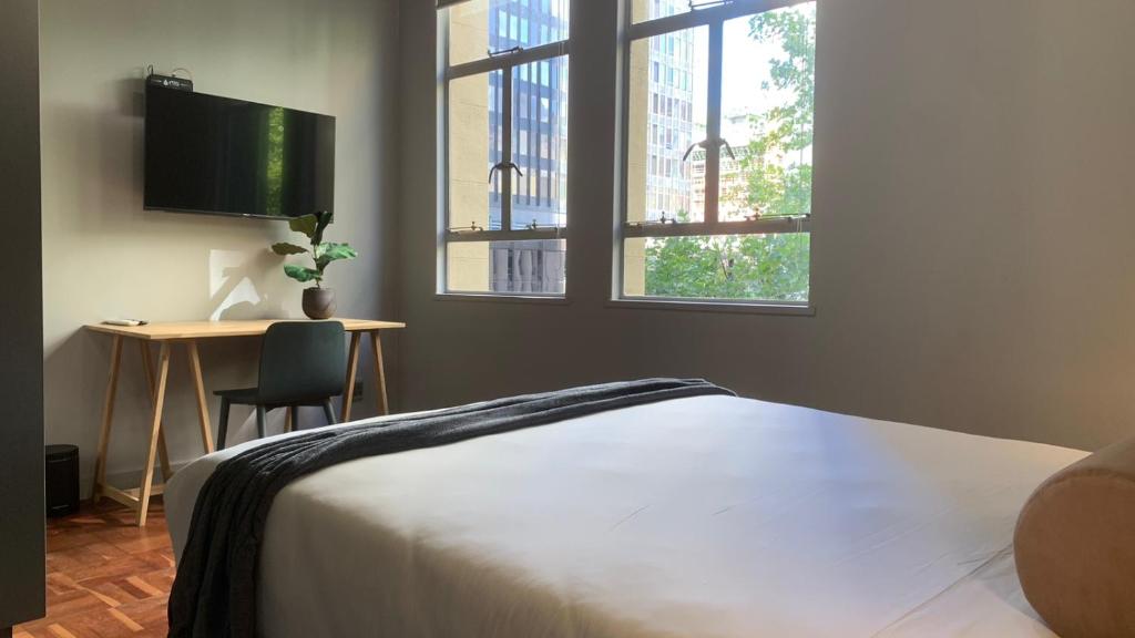 Modern Studio في كيب تاون: غرفة نوم بسرير ومكتب ونوافذ