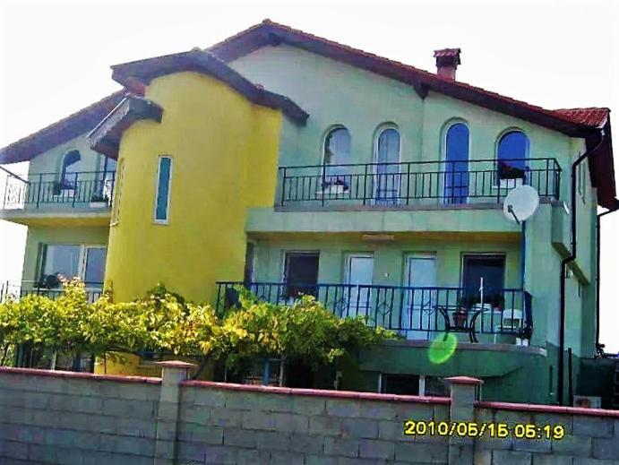 Casa grande de color blanco y amarillo con balcón en Villa Rozmarin en Balchik