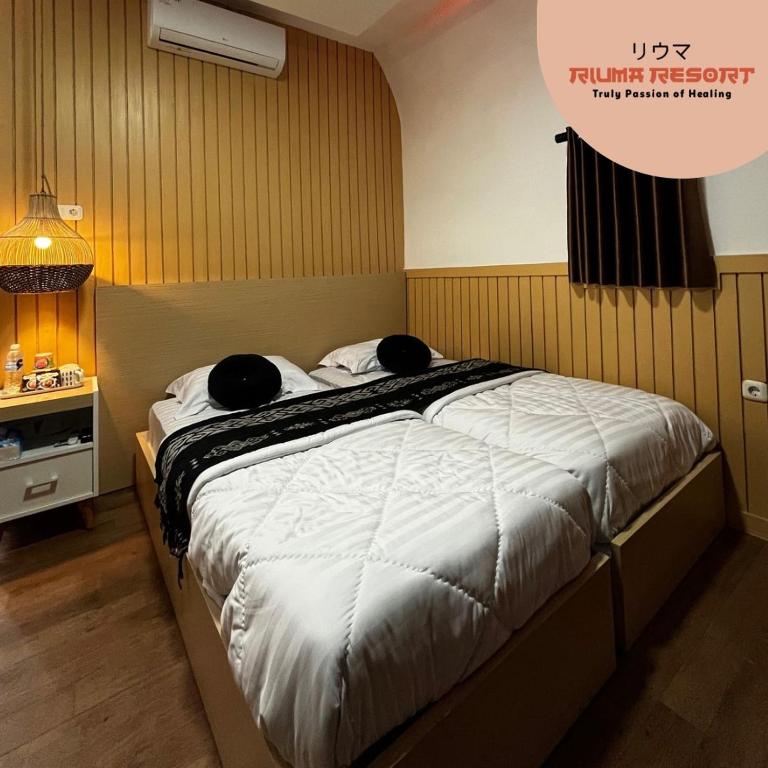 a bedroom with a bed with two pillows on it at Riuma Resort in Karangploso