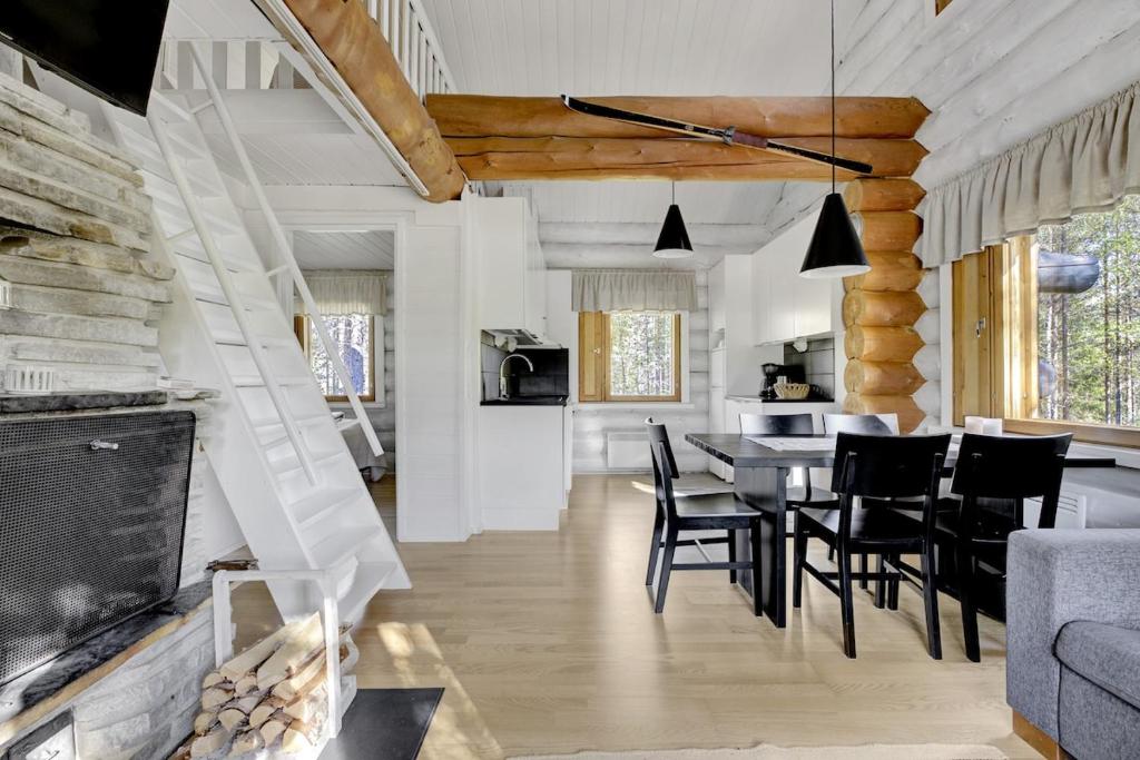 a living room with a table and chairs and a fireplace at Villa Tundra - Valkea Homes in Pyhätunturi