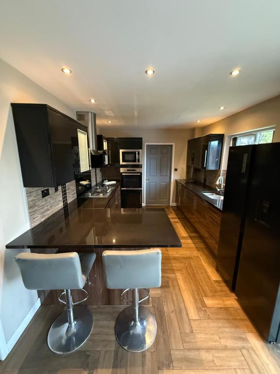 a kitchen with a black counter and two white bar stools at Willow falls in Wortley