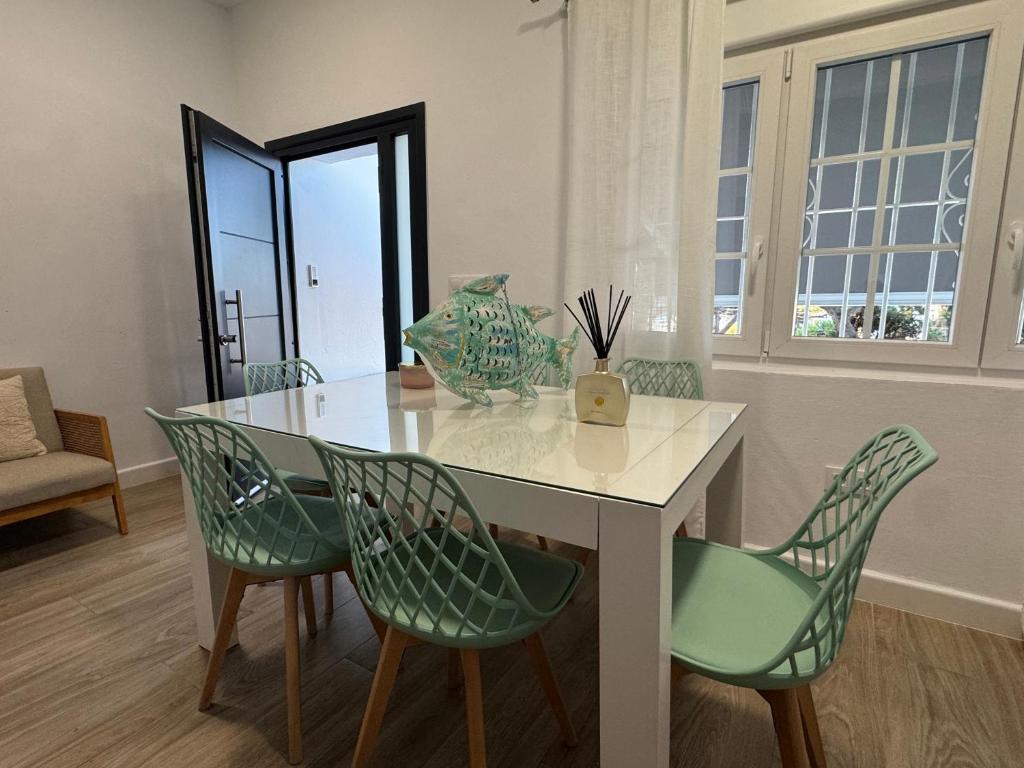 ein Esszimmer mit einem Tisch und grünen Stühlen in der Unterkunft Chalets Paraíso Playa de Mazagón Con Vistas al Mar in Mazagón
