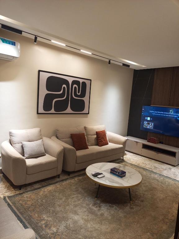 a living room with two couches and a tv at The Iconic Place in Garki