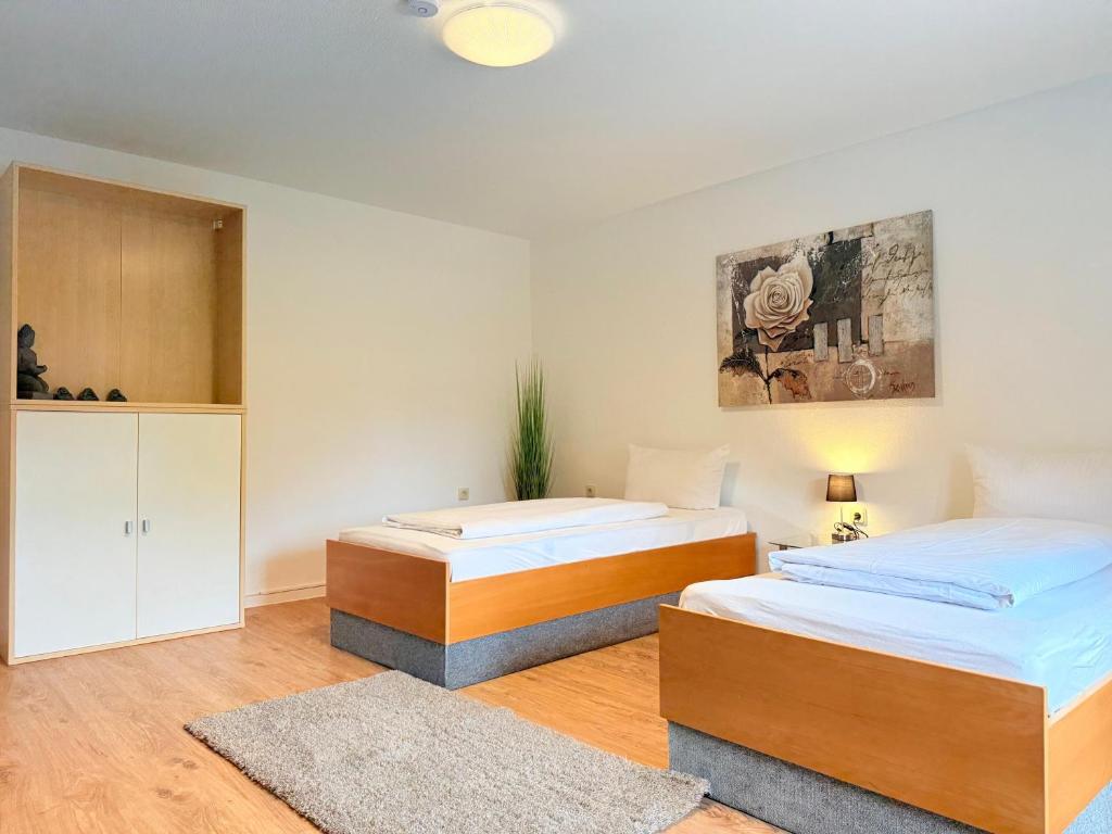 two beds in a white room with wooden floors at Hotel Alt Oesselse in Hannover