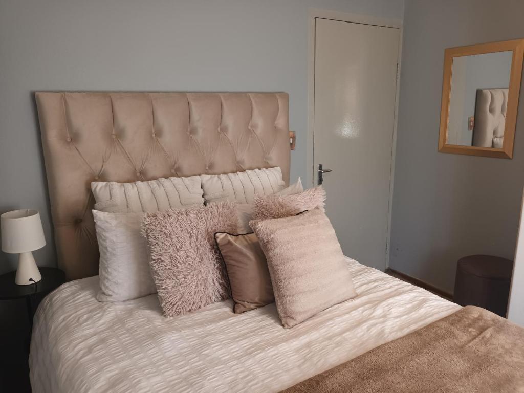 Una cama con sábanas blancas y almohadas. en Auntie Joy Home, en Pretoria