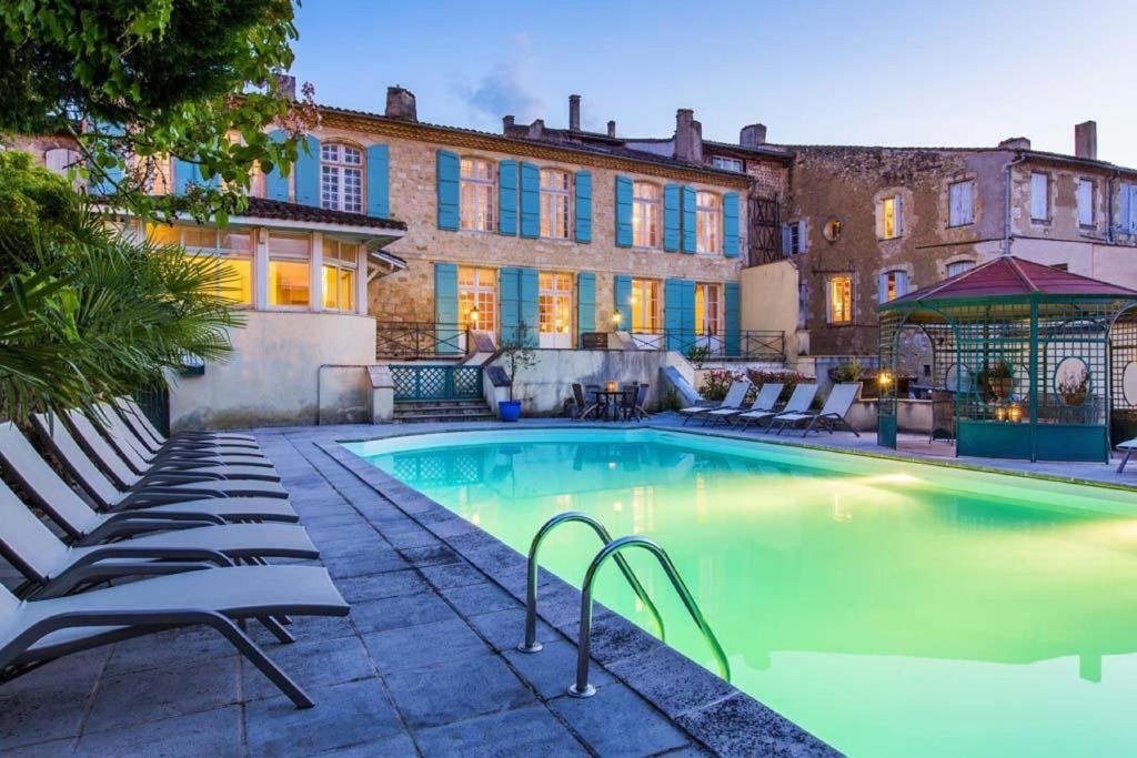 a swimming pool with lounge chairs next to a building at Les Trois Lys in Condom