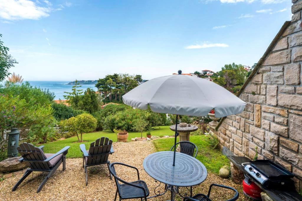 a table and chairs with an umbrella and the ocean at Entre Terre et Mer in Ciboure