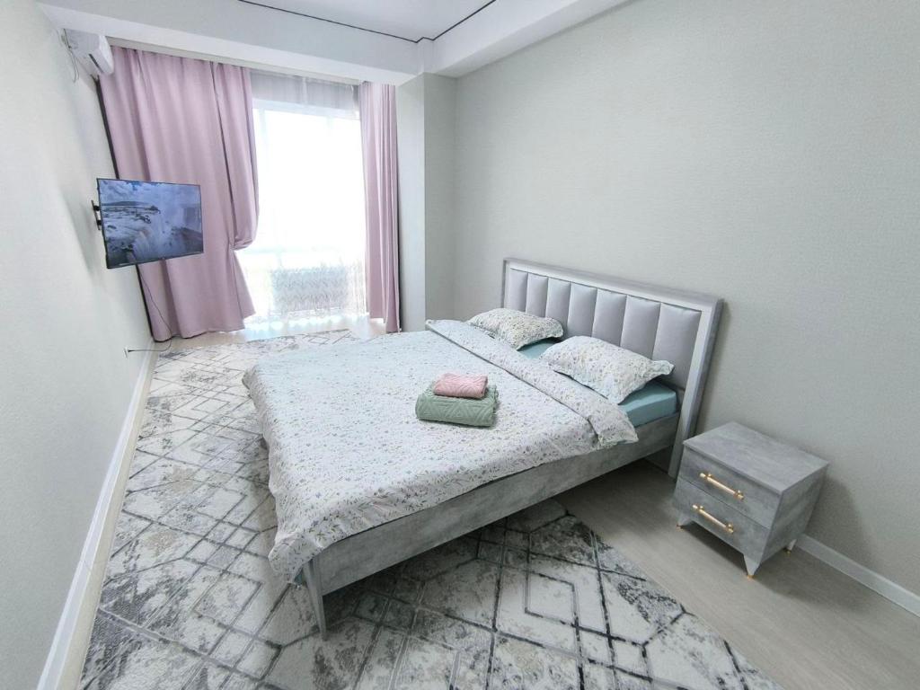 a small bedroom with a bed and a window at Квартира в новом доме недалеко от центра Бишкека in Bishkek