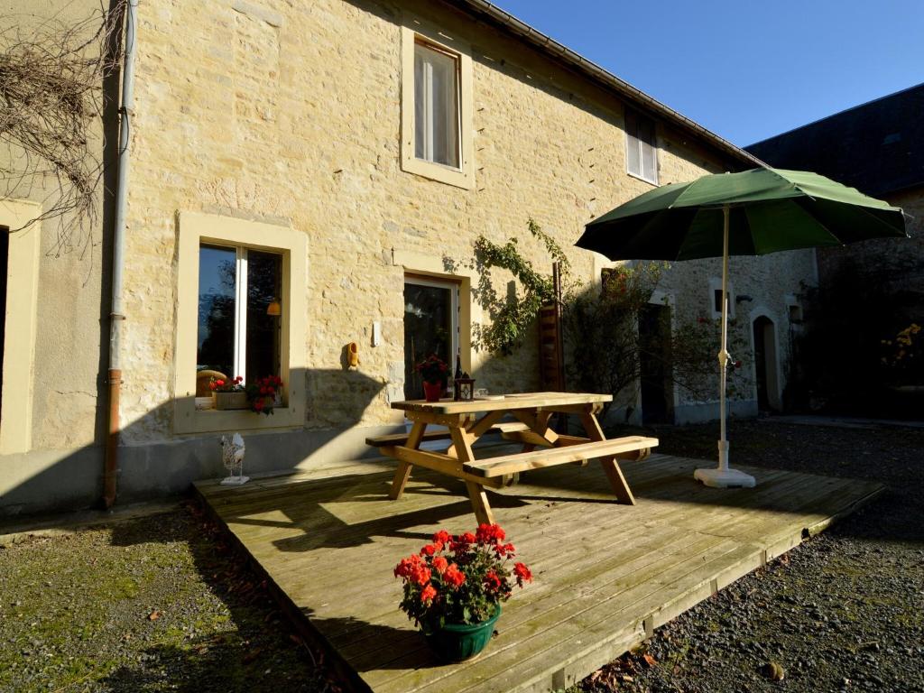 a wooden picnic table with an umbrella next to a building at Holiday Home in Saint-Clément near the Sea in Osmanville