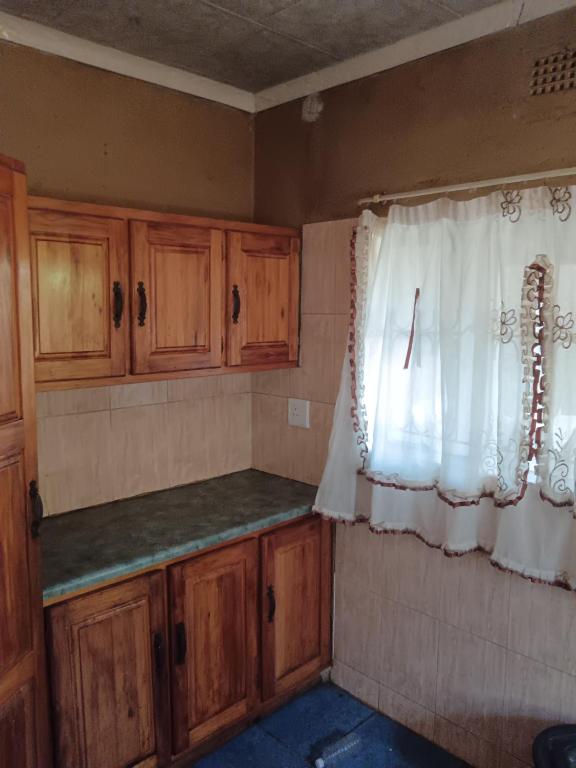 an empty kitchen with wooden cabinets and a window at Sasavona Haven in Vosburg