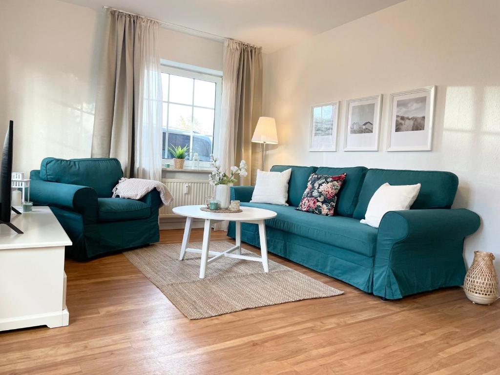a living room with a blue couch and a table at Muscheleck FeWo 2 in Döse
