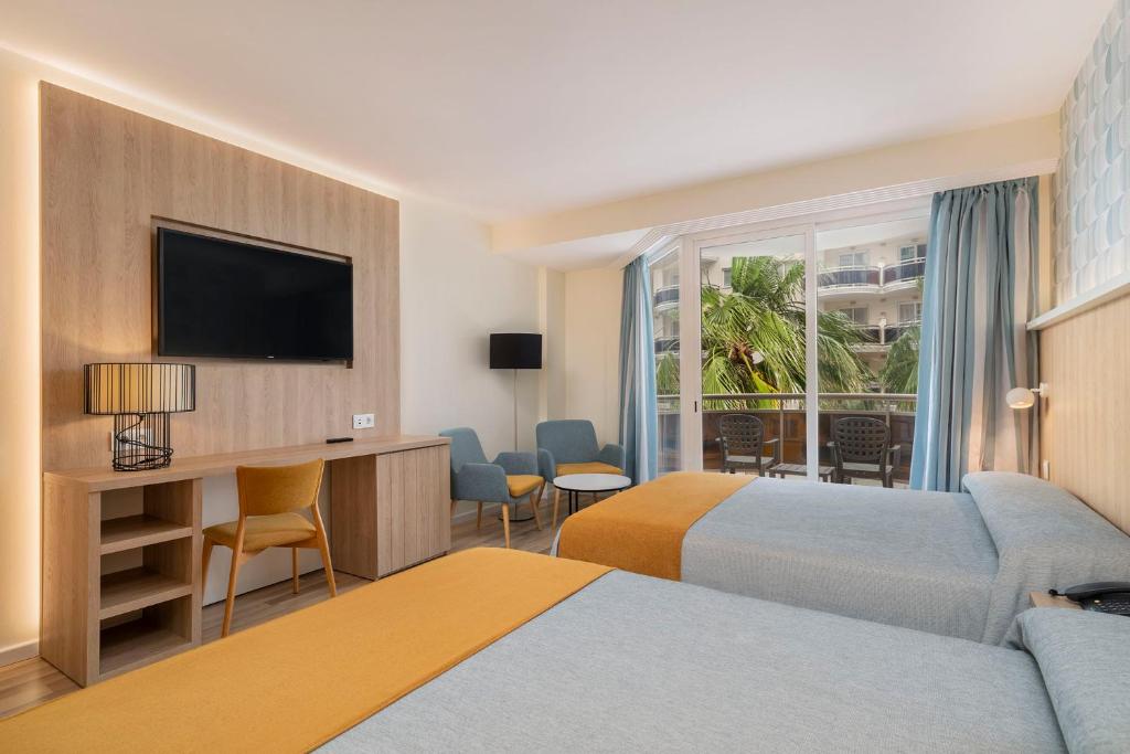 una habitación de hotel con dos camas y un televisor de pantalla plana en Peñiscola Plaza Suites, en Peñíscola