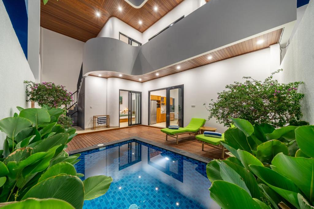 a pool in a house with green chairs and plants at Sanur Paradise - Brand New 3BR Villa - Private Pool - Beach Access in Sanur
