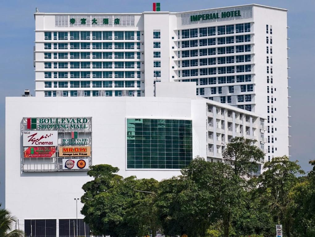 deux grands bâtiments blancs dans une ville dans l'établissement Imperial Hotel, à Bintulu