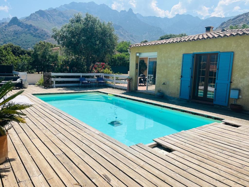 a swimming pool on a wooden deck with a house at Villa 3 chambres avec piscine et parking privés in Calenzana
