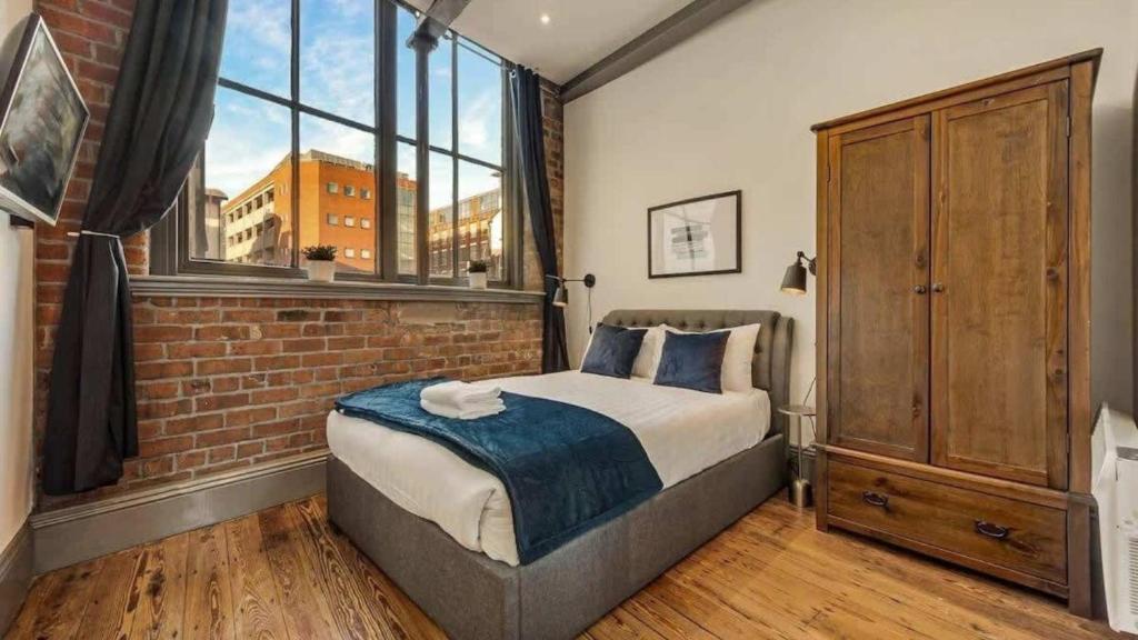 een slaapkamer met een bed en een bakstenen muur bij Bands Warehouse III - Sleeping 8 Guests! in Liverpool
